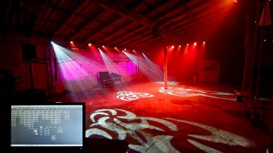 Bunte Lichtstrahlen beleuchten einen Raum mit einem Bildschirm im Vordergrund.